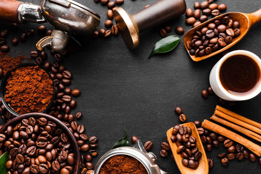 Chicchi di caffè tostati, macinino e cucchiai di legno su fondo scuro: la storia del caffè