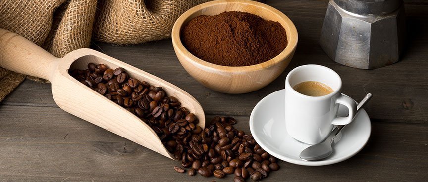 Fondi di caffè in una ciotola, chicchi su paletta di legno e tazzina di espresso