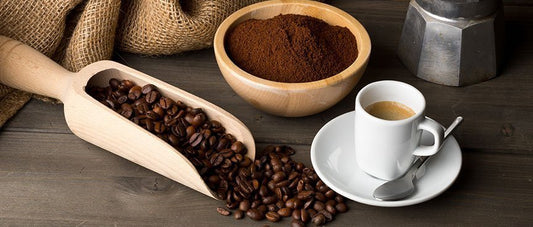 Fondi di caffè in una ciotola, chicchi su paletta di legno e tazzina di espresso